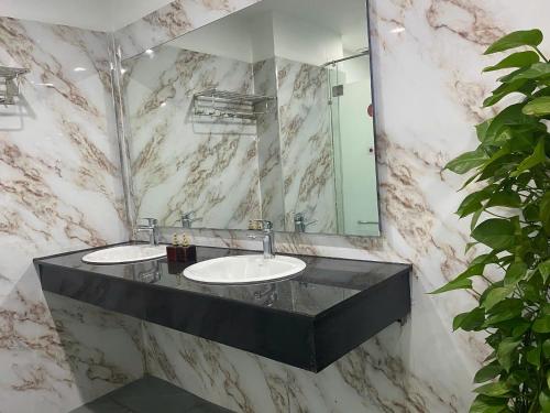 a marble bathroom with two sinks and a mirror at Quoc Cuong Hotel & Apartment Danang by Haviland in Da Nang