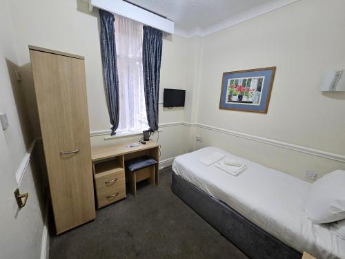 a bedroom with a bed and a desk and a window at The President Hotel in Blackpool