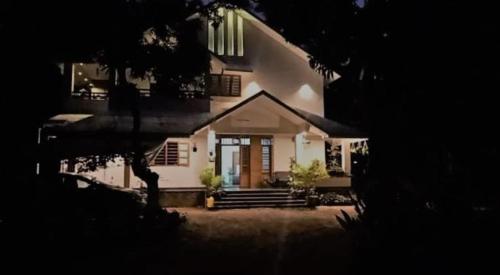 a white house with a front door and stairs at Shruthi's Aarohi-Nature's Retreat Homestay in Kannur