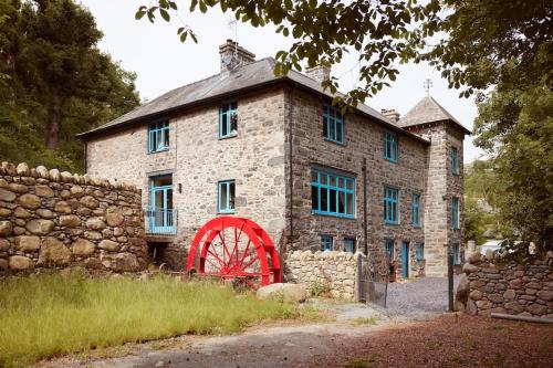 a stone building with a red wheel in front of it at Ty Pandy Eclectic Luxury Family cottage in Rowen Sleeps 10 in Conwy