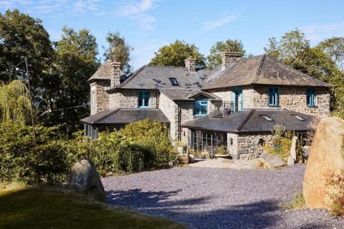 an old stone house with a driveway in front of it at Ty Pandy Eclectic Luxury Family cottage in Rowen Sleeps 10 in Conwy