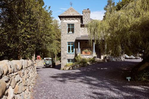 a stone house with a stone wall next to a driveway at Ty Pandy Eclectic Luxury Family cottage in Rowen Sleeps 10 in Conwy