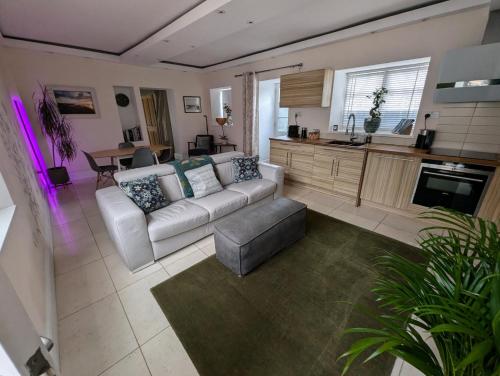 a living room with a white couch and a kitchen at The Lawns Spa Apartment in Holt