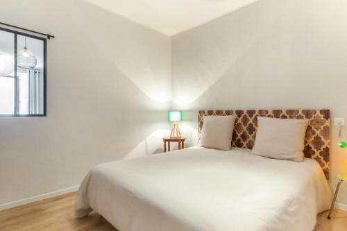 une chambre avec un grand lit blanc et une fenêtre dans l'établissement Appartement Sainte Claire Vintage - Welkeys, à Annecy