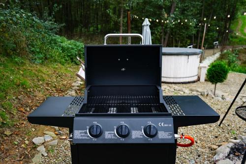 a black grill sitting in a yard with a tub at Bunkier House in Niedźwiada
