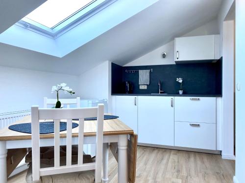 une cuisine et une salle à manger avec une table et des armoires blanches dans l'établissement Sabine´s Ferienwohnung mit Bergblick am Chiemsee, à Prien am Chiemsee