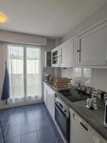 une cuisine avec des placards blancs et une grande fenêtre dans l'établissement Appartement 3 pièces cœur ville, à Quiberon
