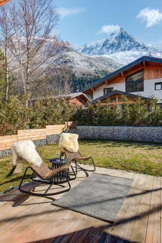 2 bancs assis sur une terrasse avec des montagnes en arrière-plan dans l'établissement Chalet Arve - Alpes Travel - Chamonix - Sleeps 10, à Chamonix-Mont-Blanc