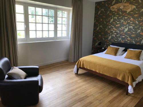a bedroom with a bed and a chair at La Grimaudière in La Chapelle-sur-Erdre