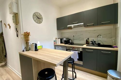 une cuisine avec une table et une horloge au mur dans l'établissement Appart Hôtel Lille Beaux Arts - Mireille, à Lille