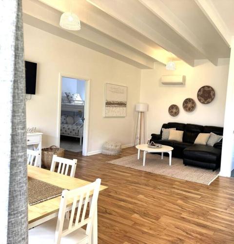 a living room with a black couch and a table at Shoaly House Cottage - A charming coastal escape in Shoal Bay