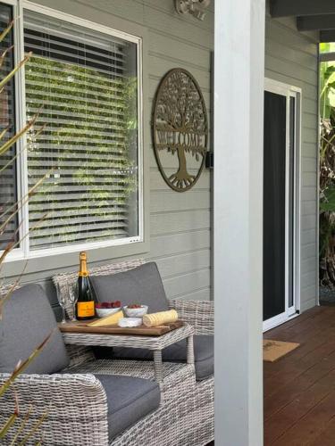 a patio with a table and a bottle of wine at Shoaly House Cottage - A charming coastal escape in Shoal Bay