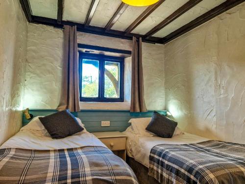 two beds in a room with a window at Clyne Farm Centre in The Mumbles