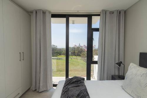 una camera da letto con un letto e una grande finestra di Boardwalk Bungalow a Gqeberha