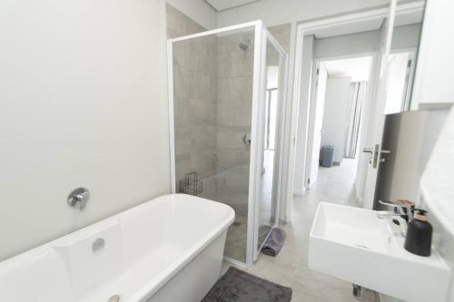un bagno bianco con vasca e lavandino di Boardwalk Bungalow a Gqeberha