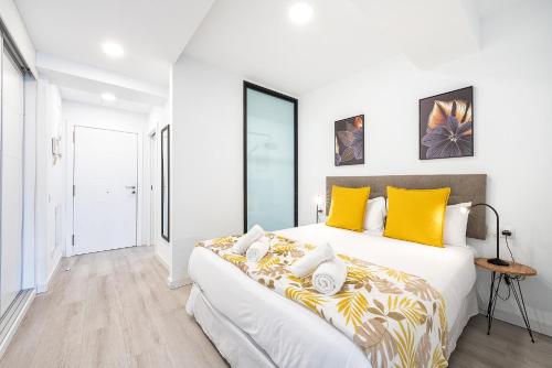 ein weißes Schlafzimmer mit einem großen Bett und gelben Kissen in der Unterkunft Castle Bank By CanariasGetaway in Guanarteme