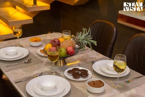 a table with plates of food and glasses of wine at Crystalline by VEO - Part of StayVista with Kids Room in Alibaug