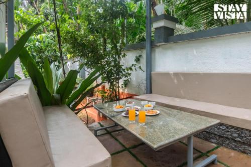 a table with glasses of orange juice on a patio at Crystalline by VEO - Part of StayVista with Kids Room in Alibaug