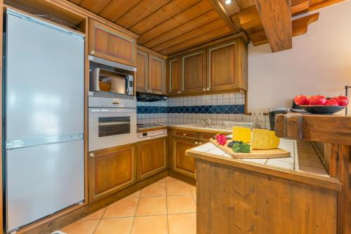 une cuisine avec des armoires en bois et un réfrigérateur blanc dans l'établissement Résidence Le Cristal - Mont Blanc 13 - Happy Rentals, à Chamonix-Mont-Blanc