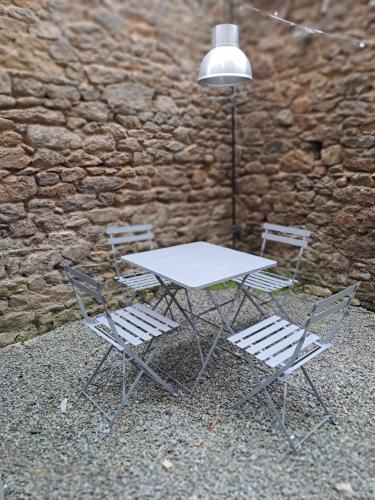 une table, deux chaises et une lampe à côté d'un mur en pierre dans l'établissement Studio Dinard, à Dinard