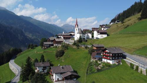 a small village on a green hill with a church at Haus Guglprasta in Sankt Veit in Defereggen