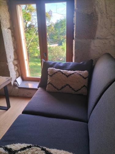 a couch with a pillow in front of a window at Chez Marie in Saint-Martin-de-Lerm