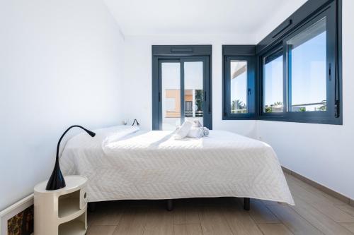 a white bedroom with a large bed and large windows at Villa Puerto Blanco in Vinaròs