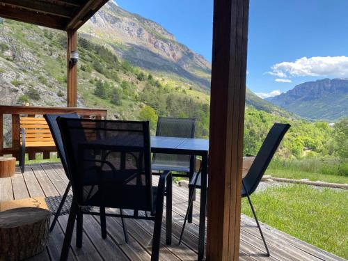 a table and chairs on a deck with a view at Chalet à un endroit exceptionnel, Alpes, Parc National des Ecrins in Les Vigneaux