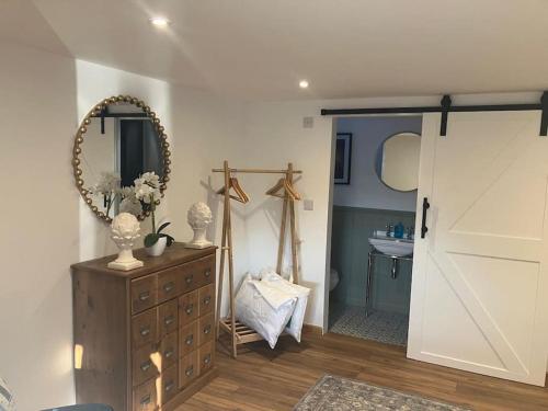 a bathroom with a dresser and a mirror and a door at Wood Lodge in Bungay