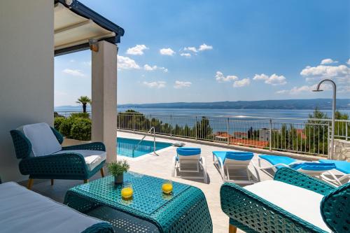 a patio with chairs and tables and a swimming pool at Seaview villa Marija in Duće