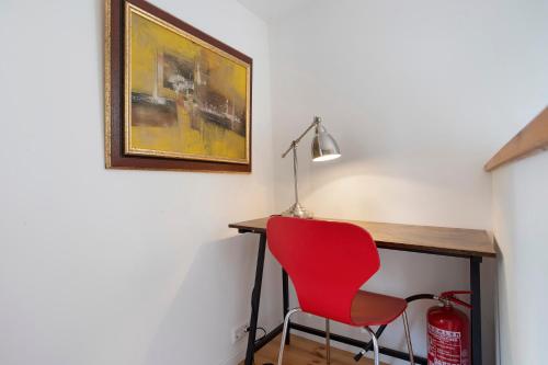 a red chair sitting next to a desk with a lamp at Taubenkobel in Groß Wokern