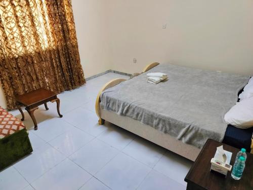 a bedroom with a bed and a chair and a table at Private Guest Room in Kuwaitat in Al Ain