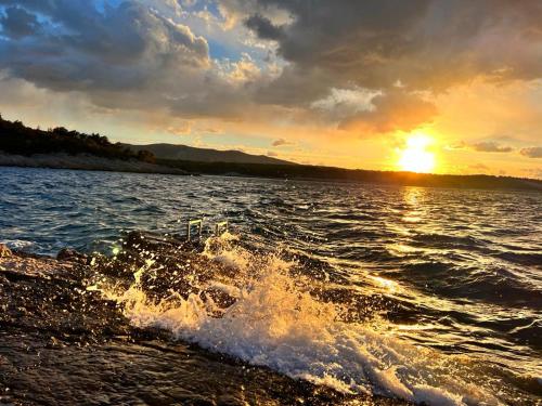 a sunset over a body of water with the waves at Hvaretta Villas in Stari Grad