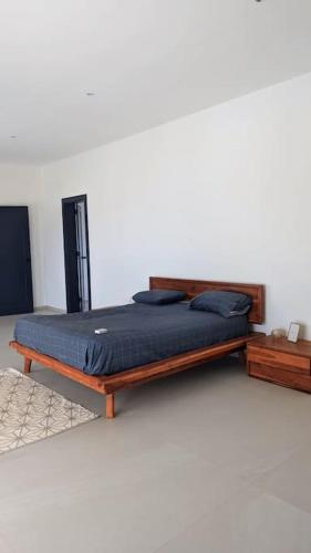 a bed with a wooden frame in a room at La Villa Relax - Maison neuve en bordure de mer à Guereo in Guéréo