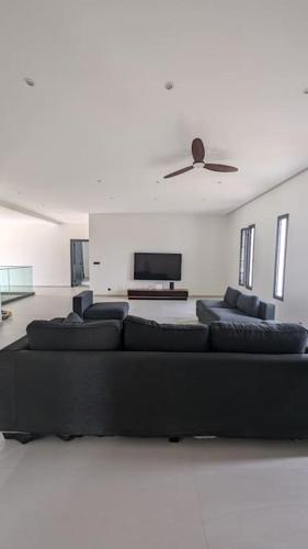 a living room with a black couch and a tv at La Villa Relax - Maison neuve en bordure de mer à Guereo in Guéréo