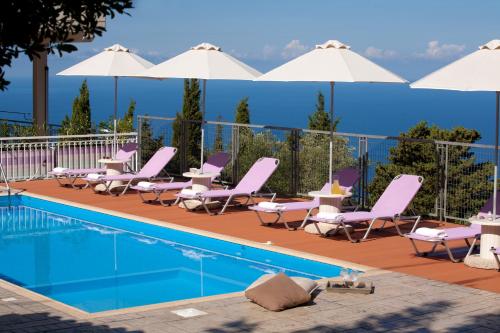 a pool with chairs and tables and white umbrellas at Amalia Apartments in Exanthia