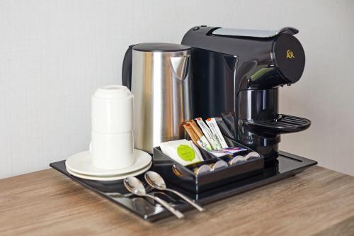 a coffee maker on a black tray with spoons at Hesperia Sevilla in Seville