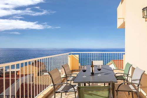 a balcony with a table and chairs and the ocean at villa com piscina entre o mar e as montanhas in Paul do Mar