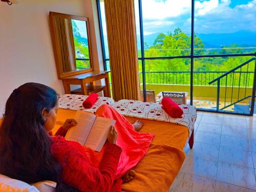 a young girl sitting on a couch reading a book at Awinco Haputale in Haputale