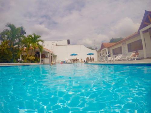 a large blue swimming pool with chairs and umbrellas at Hotel Villa Ricaurte in Girardot