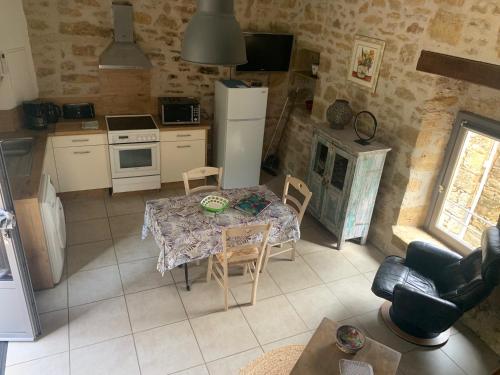 une cuisine avec une table et des chaises ainsi qu'une cuisine avec une cuisinière dans l'établissement Gîte de Camboulit, à Camboulit
