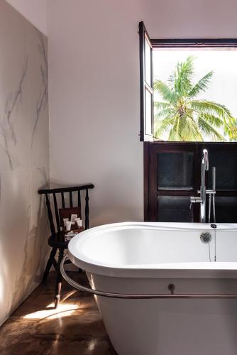 a white bath tub in a bathroom with a window at Kisiwa House in Zanzibar City