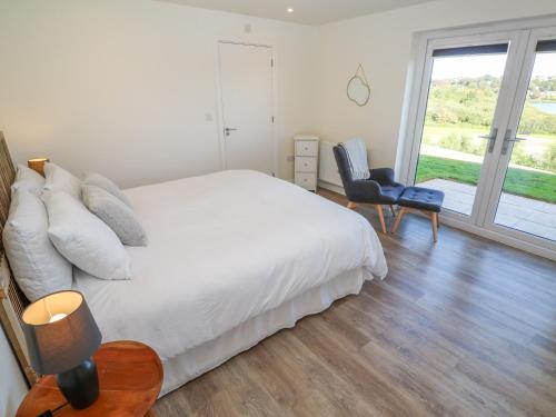 Un dormitorio con una cama y una silla y una ventana. en 2 The Dunes, en Falmouth