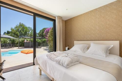 a bedroom with a large bed and a pool at La Villa Monarque in Cap d'Agde
