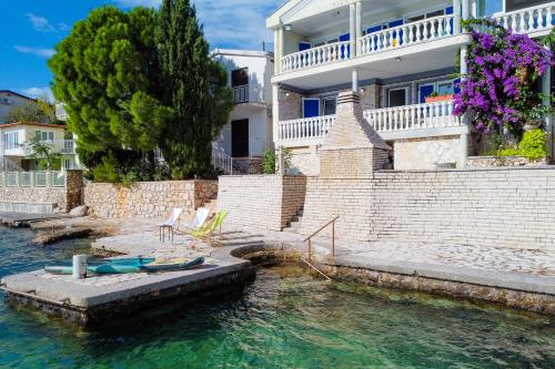 una casa en el agua con un barco delante en Holiday Home Seafront Escape - Happy Rentals, en Šibuljina