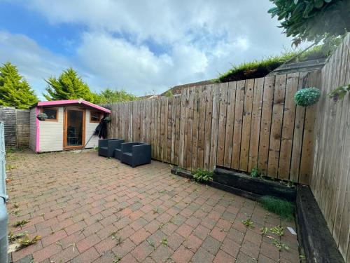 a backyard with a fence and a pink house at The Cozy Retreat in Hyde Park