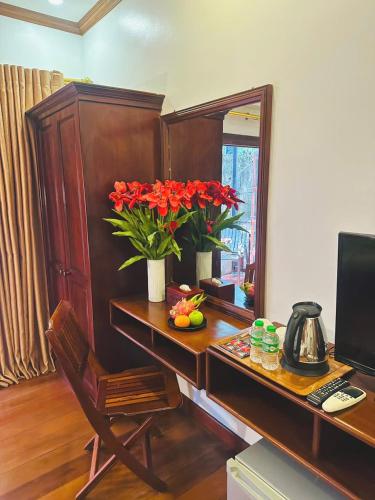 a desk with a computer and red flowers on it at Luang Prabang Mekong Charm River View in Luang Prabang