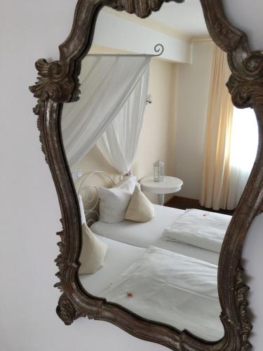a bedroom with a white bed with a mirror at Boutique-garni Hotel Papillon in Kempen