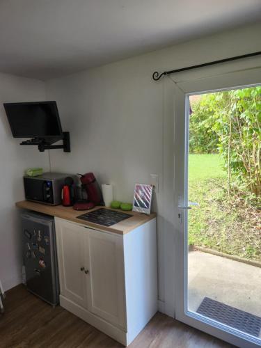 une cuisine avec un comptoir et une porte donnant sur une cour dans l'établissement Studio sur les fleuristes, à Cambo-les-Bains