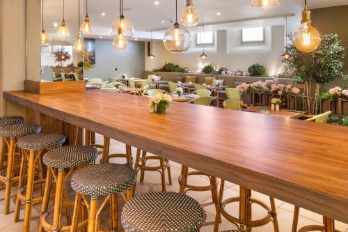 a large wooden bar in a restaurant with stools at Catalonia Santa Justa in Seville